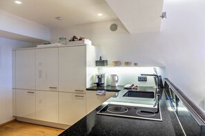 A modern kitchen with white cabinets, a black countertop, a built-in stove, a kettle, and a coffee maker. - Apartment "Haus Excelsior Top 38" with Mountain View, Balcony & Wi-Fi (Seefeld in Tirol)