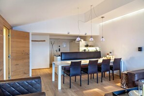 A modern living space with a dining area, a kitchen in the background, and a wooden door. - Apartment "Haus Excelsior Top 38" with Mountain View, Balcony & Wi-Fi (Seefeld in Tirol)