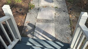 A pathway leading to a wooden deck with a railing.