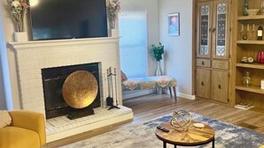 A living room with a fireplace, a television, a sofa, a coffee table, and a cabinet with glass doors.
