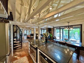 Cocina amplia con una isla grande, horno integrado y comedor con vistas al exterior.