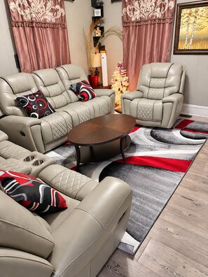 A living room with a sofa set, a coffee table, and a decorative rug. - High Ceilings | King Beds | 85” TV | Near Downtown (Winston-Salem)
