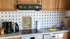 Une cuisine avec des meubles de rangement en bois, un pare-feu en carreaux, une machine à café, un grille-pain et un lave-vaisselle.