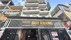 Un hotel llamado 'Hotel Duý Khàng' con un letrero que muestra información de contacto y una escalera que lleva a la entrada.