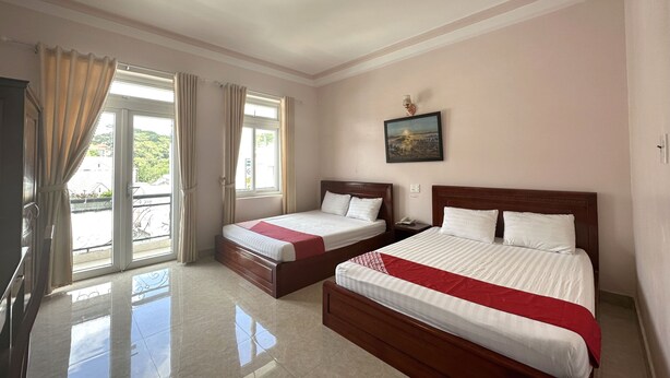 Una habitación de hotel con dos camas, un ventanal con cortinas, un cuadro en la pared y una lámpara en el techo.