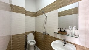 Un baño con inodoro, lavabo, ducha y espejo.