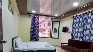 A bedroom with a bed, a wooden bench, a marble floor, and a view of the outside. - Samriddhi Hotel Banquet and Lawn (Varanasi)
