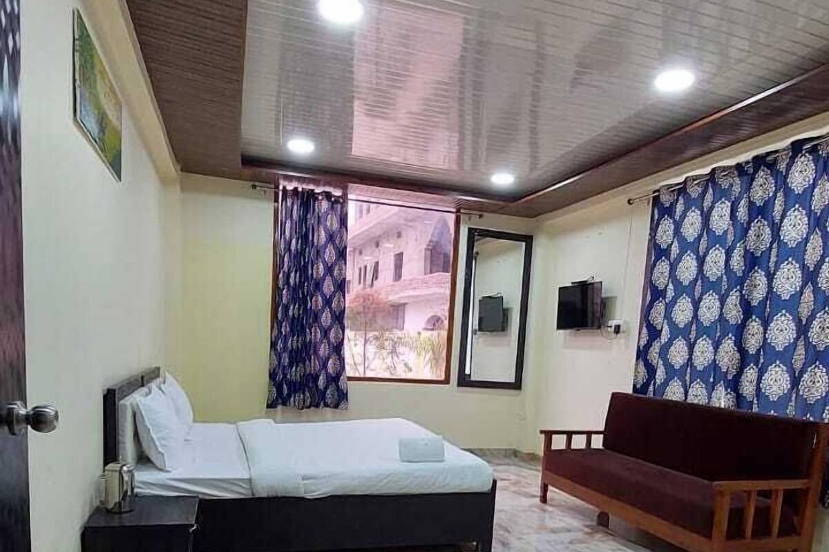 A bedroom with a bed, a wooden bench, a marble floor, and a view of the outside.