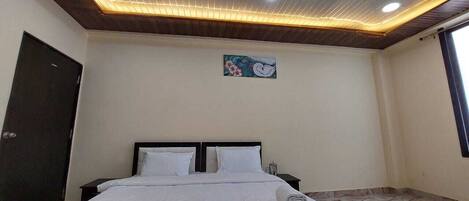 A bedroom with a bed, a nightstand, a door, and a wall-mounted artwork.