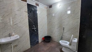 A bathroom with a sink, toilet, and shower area. - Samriddhi Hotel Banquet and Lawn (Varanasi)