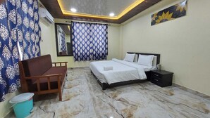 A bedroom with a bed, bedside table, and a chair. - Samriddhi Hotel Banquet and Lawn (Varanasi)