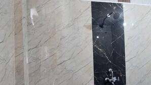 A bathroom with a white sink, a black marble wall, and a wooden panel border. - Samriddhi Hotel Banquet and Lawn (Varanasi)