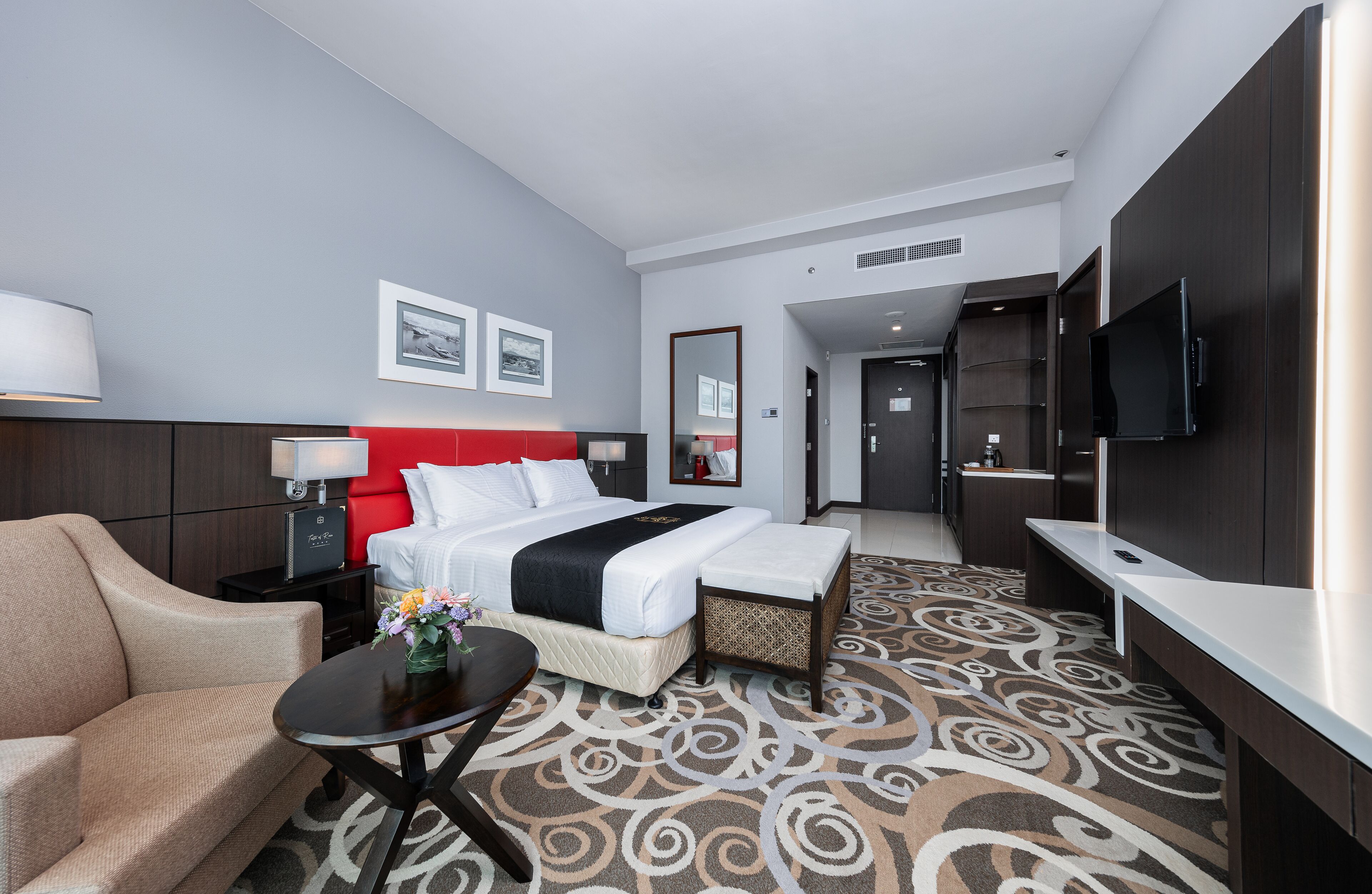 A hotel room with a bed, a sofa, a TV, and a desk.
