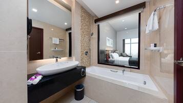 A modern bathroom with a large sink, a bathtub, and a mirror reflecting a bedroom.