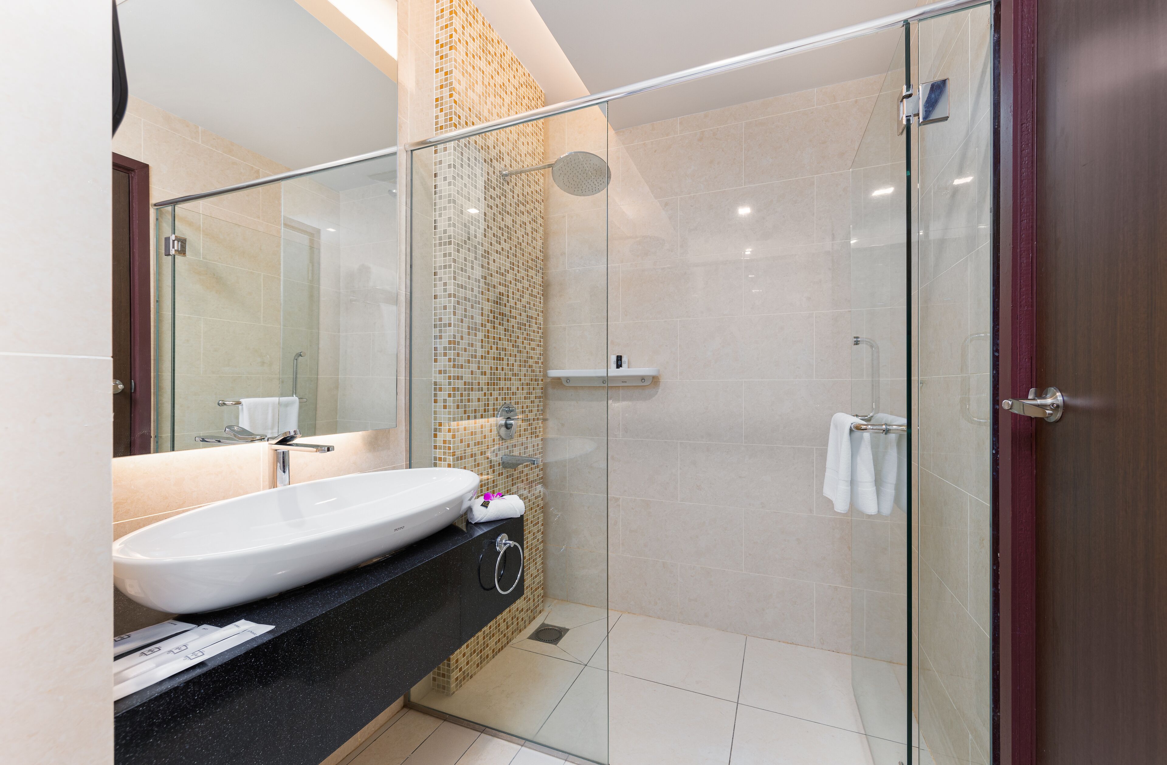A modern bathroom with a glass-enclosed shower, a large sink, and a mirror.