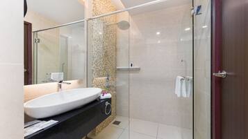 A modern bathroom with a glass-enclosed shower, a large sink, and a mirror.