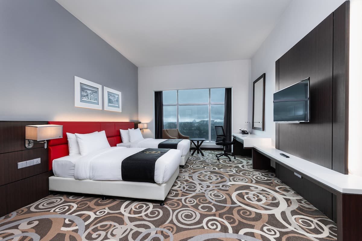 A hotel room with a large bed, a desk, a chair, and a TV.