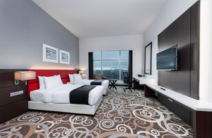 Una habitación de hotel con una cama grande, un escritorio, una silla y un televisor.