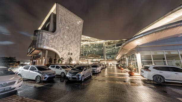 A modern building with a curved facade and a parking lot with several cars. - Raia Hotel & Convention Centre Kuching (Kuching)