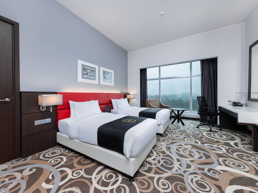 A hotel room with two beds, a desk, a chair, and a large window.