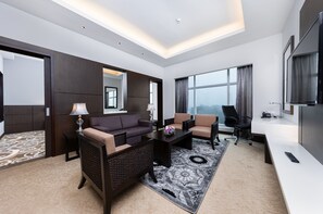 A modern hotel room with a sofa, armchair, desk, and large windows. - Raia Hotel & Convention Centre Kuching (Kuching)