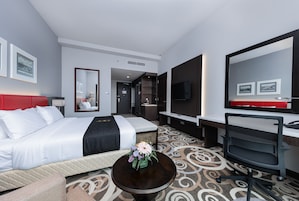 Una habitación de hotel con cama, escritorio, silla, televisor y espejo.