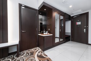 A hotel room with a large wardrobe, a small vanity with a mirror, and a built-in shelf with toiletries. - Raia Hotel & Convention Centre Kuching (Kuching)
