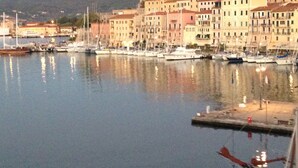A marina with boats docked, buildings with balconies, and a mountainous backdrop. - The Rooms by the Sea (Portoferraio)