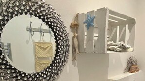 A bathroom with a large mirror, a sink, and a small shelf with towels. - The Rooms by the Sea (Portoferraio)