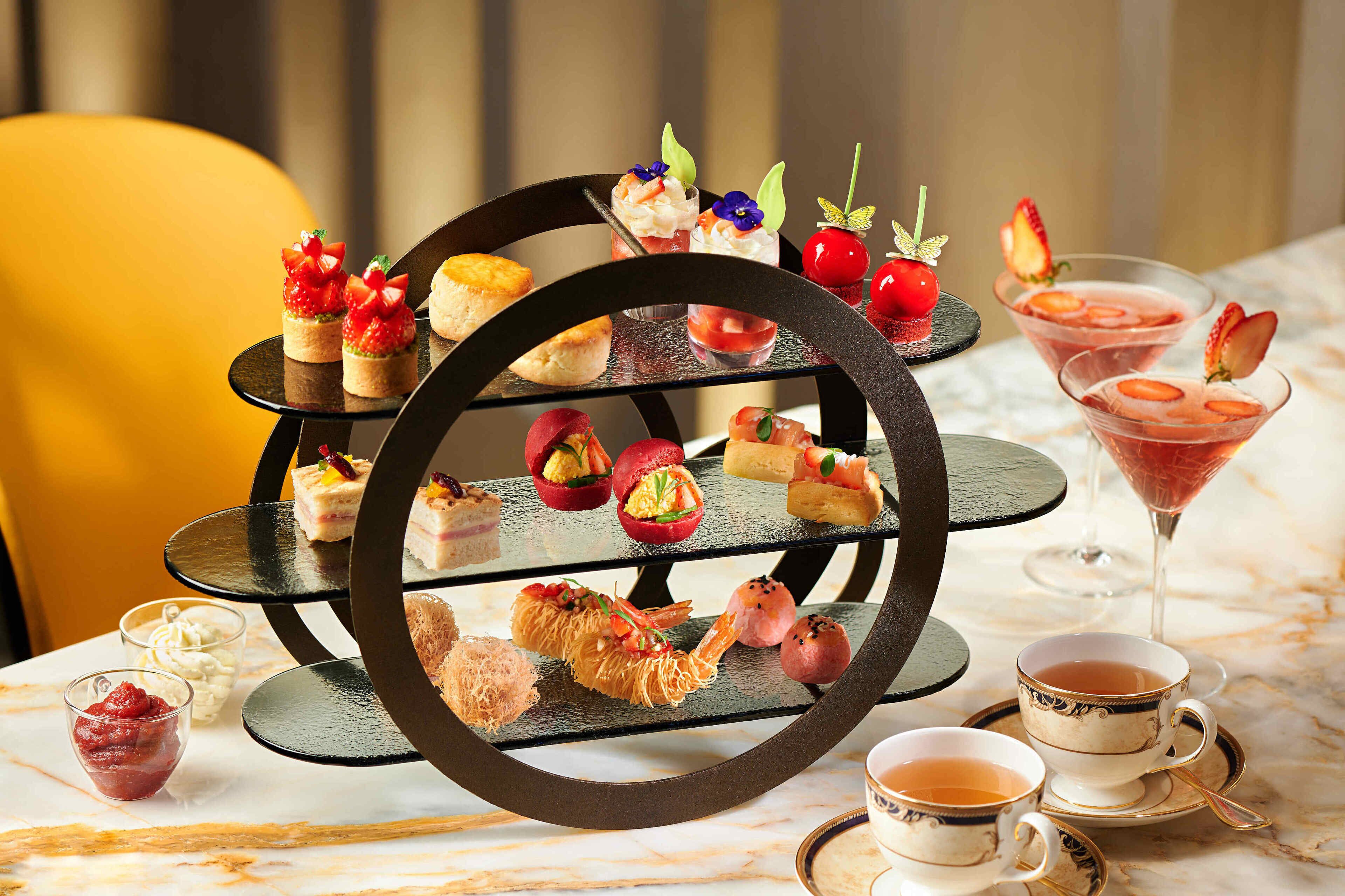 Un expositor de postres de varios niveles con diversas pastelerías y bebidas.