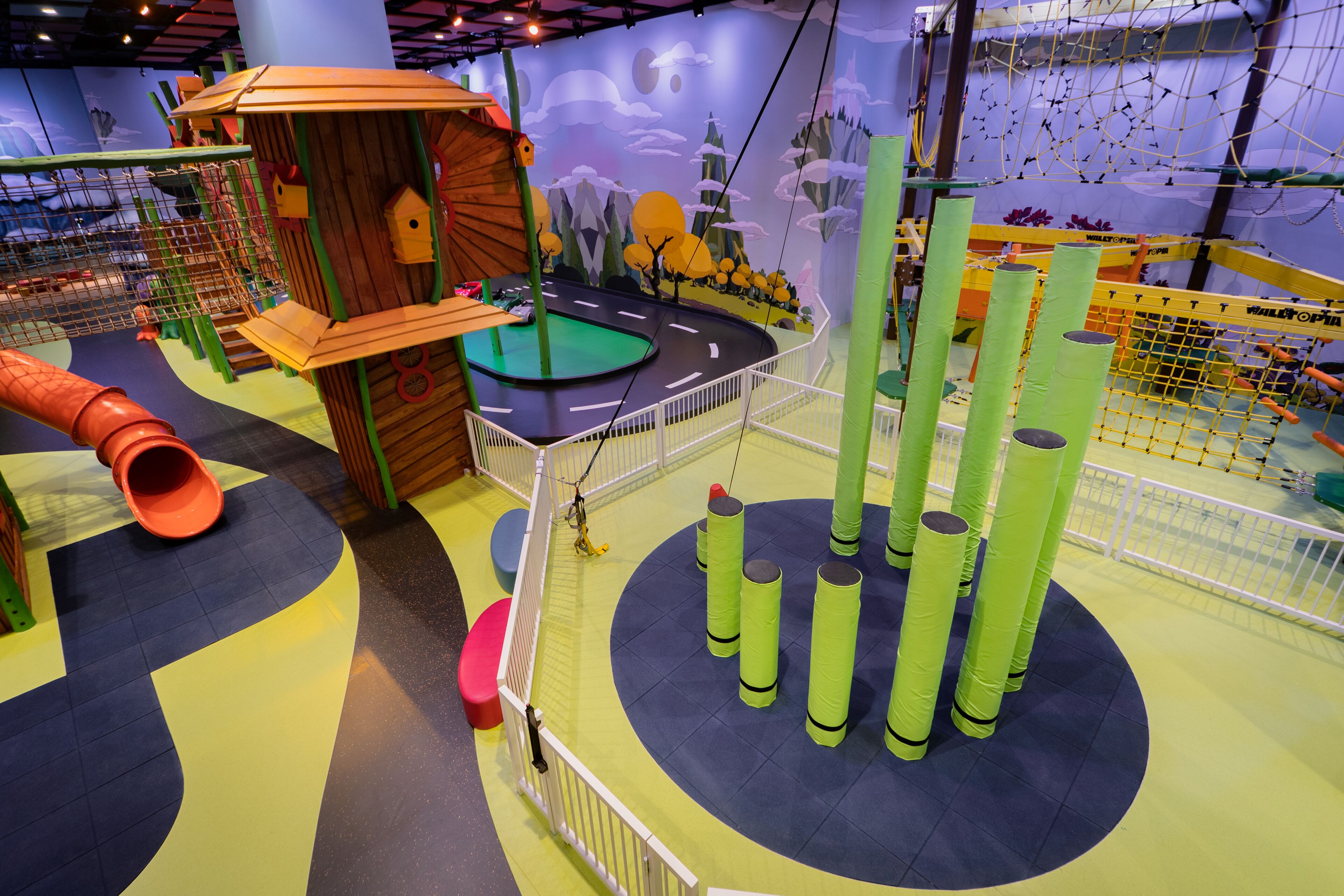 A children's play area with a slide, climbing structures, and a netted obstacle course.