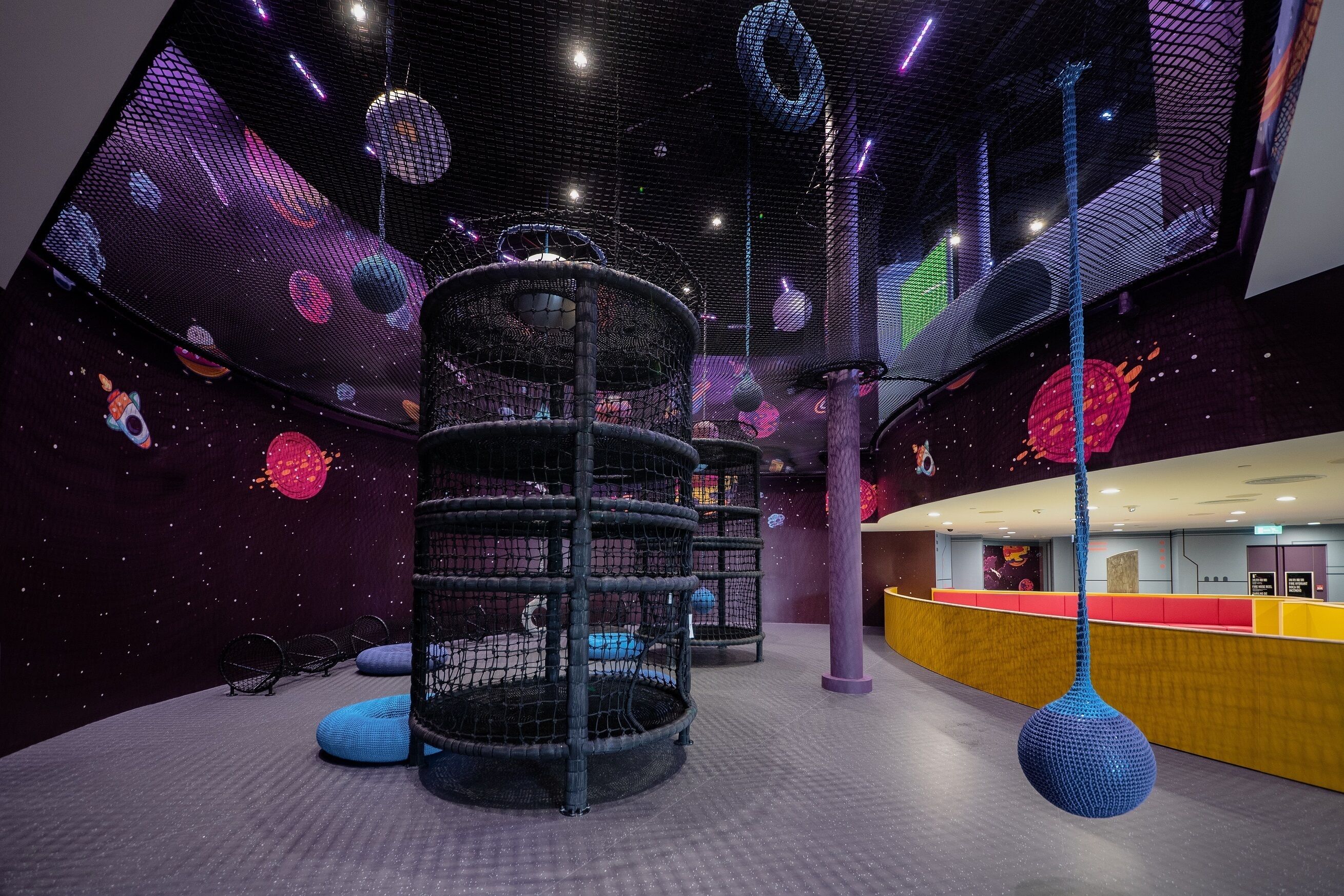 A play area with a net structure, a hanging spherical object, and a counter with a red and yellow color scheme.