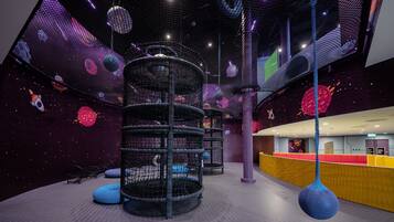 A play area with a net structure, a hanging spherical object, and a counter with a red and yellow color scheme.