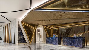 A modern hotel lobby with marble reception desks, geometric ceiling design, and a clean, polished floor. - Epic Tower - Studio City Macau (Cotai)
