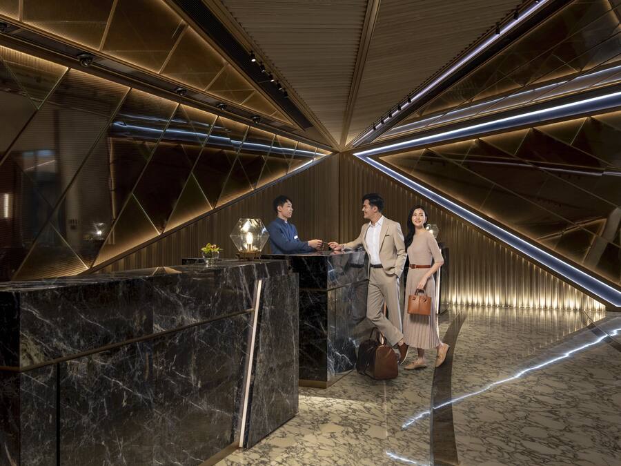 A modern reception area with a marble reception desk, geometric lighting, and a polished floor.