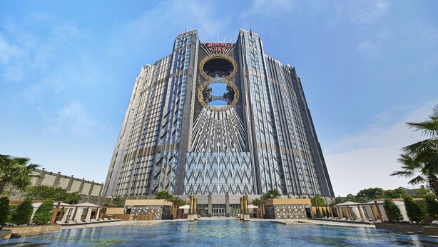 A modern hotel with a distinctive circular skylight and a large swimming pool in the foreground. - Epic Tower - Studio City Macau (Cotai)
