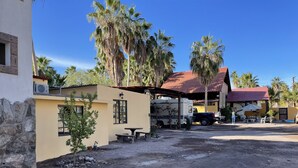 A rural setting with a dirt ground, a stone wall, and a yellow building with a red roof. - Casa arroyo at Bajazul just steps of waterfront and downtown (Loreto)