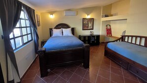 A bedroom with a bed, a bedside table, a chair, a window with curtains, a wall-mounted air conditioner, and a painting. - Casa arroyo at Bajazul just steps of waterfront and downtown (Loreto)