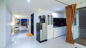 A modern kitchen with a refrigerator, coffee maker, and cabinets. - Beststayinphuket Poolview (Patong)