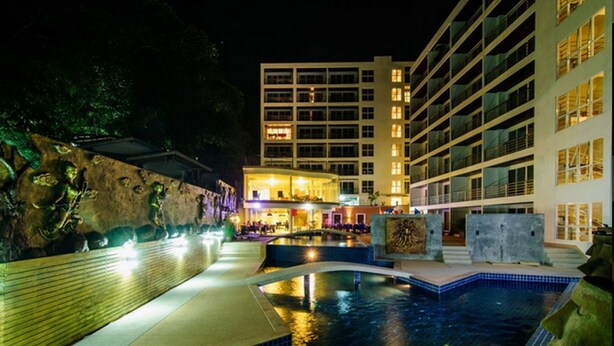 A swimming pool area with a stone wall and a building in the background. - Beststayinphuket Poolview (Patong)