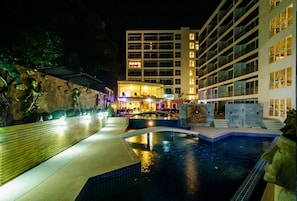 Uma área de piscina com um muro de pedra e um edifício ao fundo.