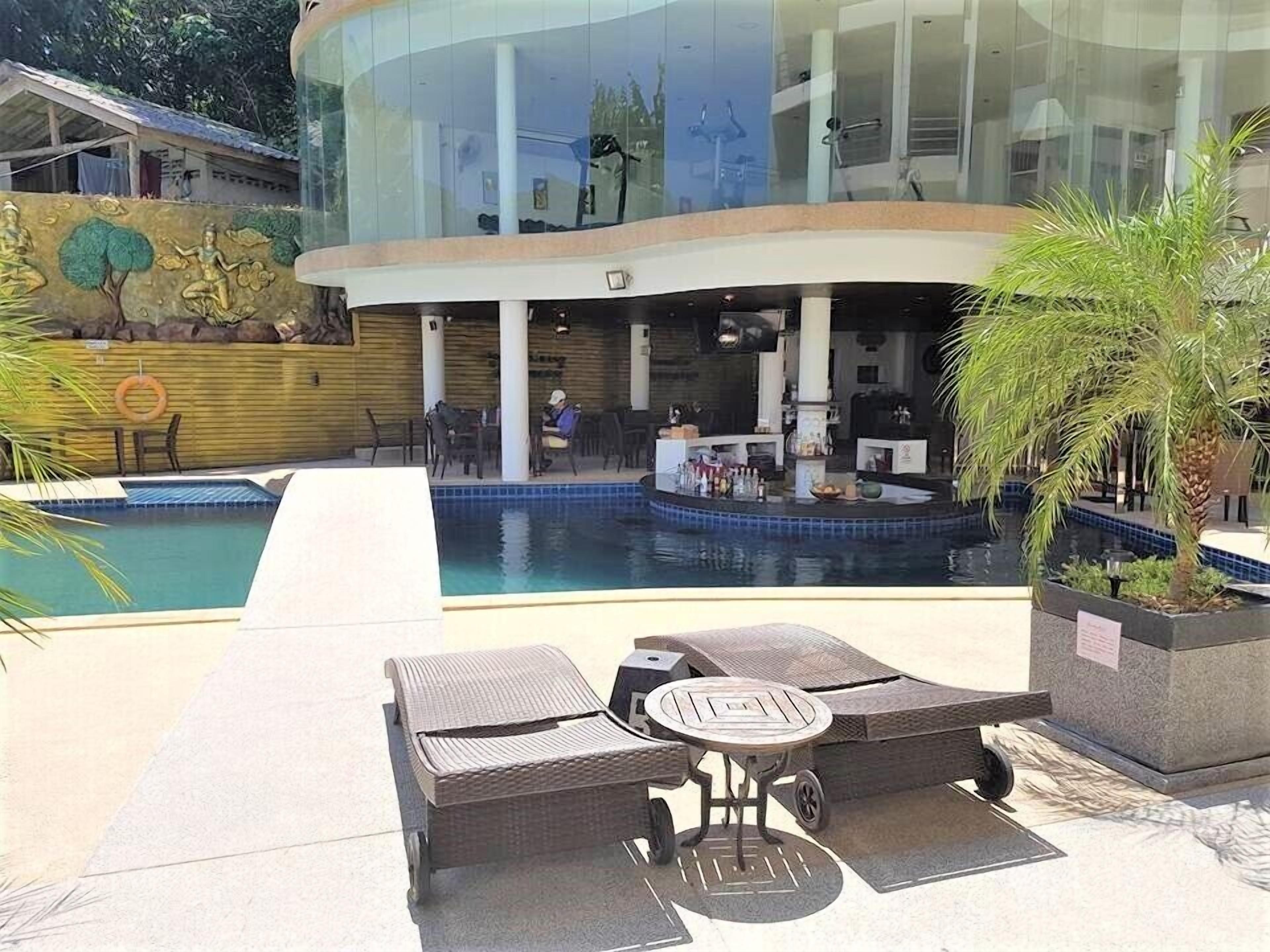 A modern hotel with a swimming pool, lounge chairs, and a bar area.