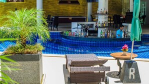 A poolside area with a bar, lounge chairs, and a potted plant. - Beststayinphuket Poolview (Patong)