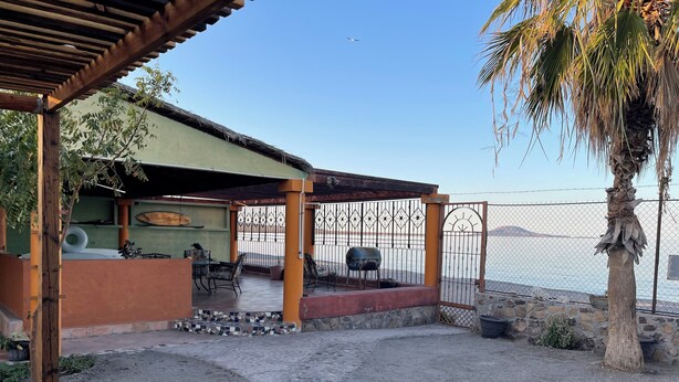 Een terras met een overdekte zithoek, een barbecue en uitzicht op zee.