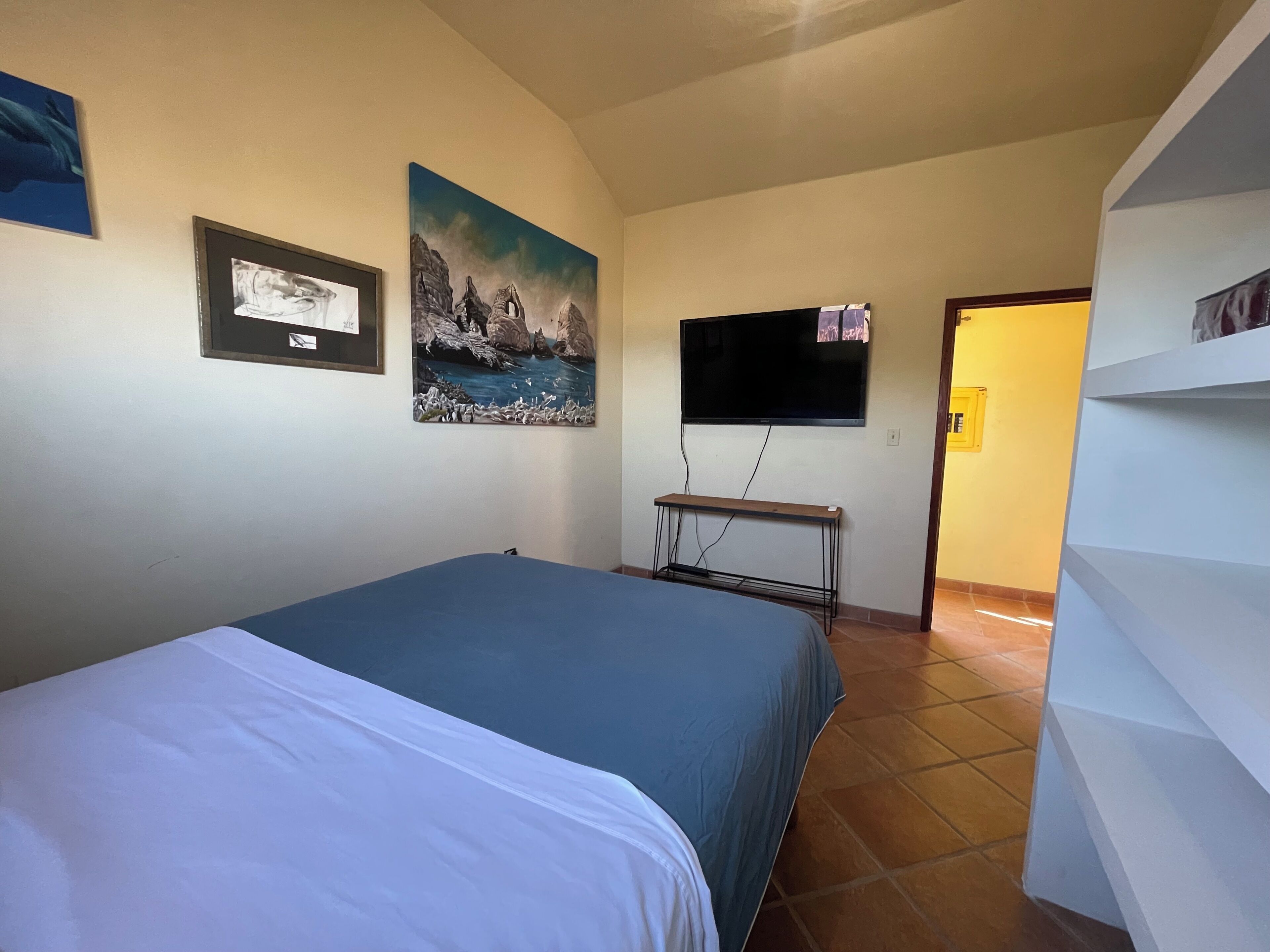 Ein Schlafzimmer mit einem Bett, einem Fernseher und einem Gemälde an der Wand.