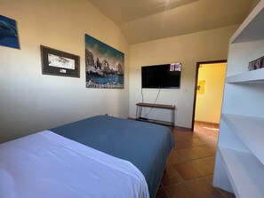A bedroom with a bed, a TV, and a painting on the wall. - Charming 2-bedroom house in Loreto on the beach, just steps from the water. (Loreto)