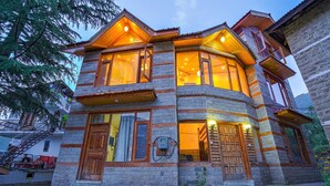 Un immeuble en pierre à plusieurs étages, doté de balcons en bois et de grandes fenêtres.