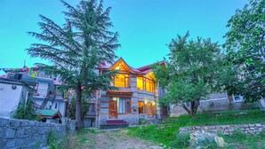 Une maison à deux étages avec une façade en pierre, des portes en bois et un toit rouge.