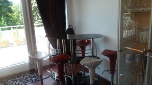 Un espace bar moderne avec un présentoir en verre, des tabourets de bar rouges et une table ronde.