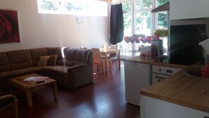 Un salon avec un canapé, une table à manger avec des chaises, une cuisine équipée d’un four à micro-ondes et une fenêtre avec des rideaux.